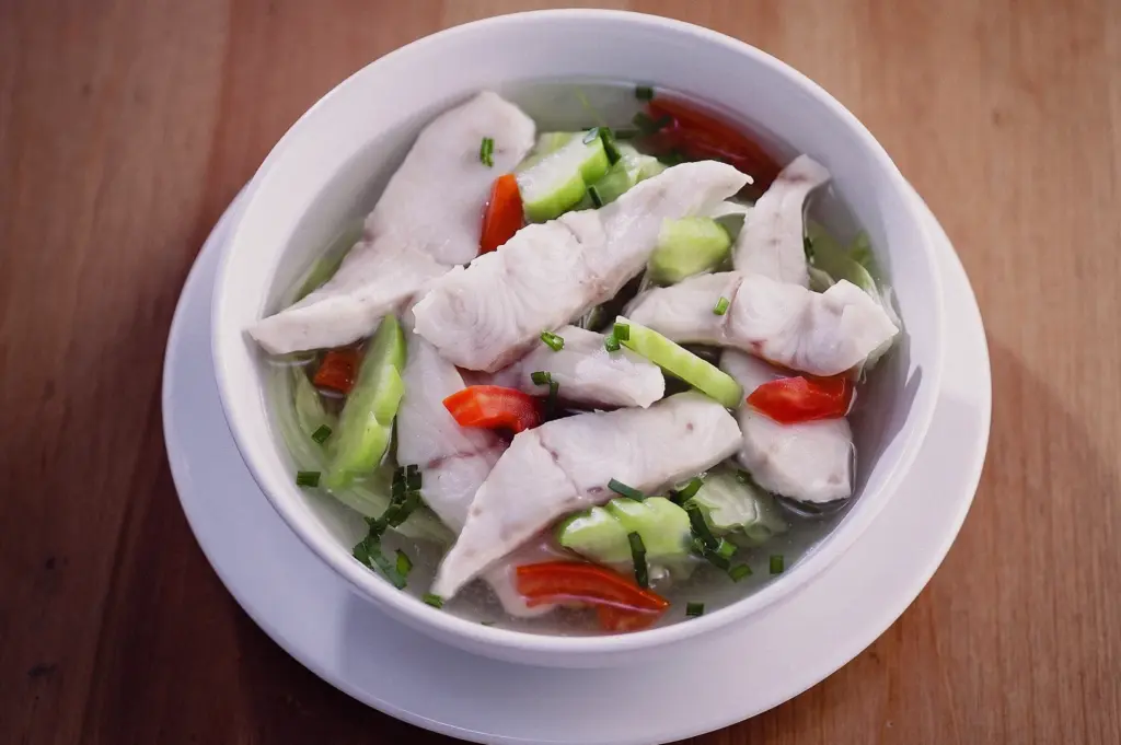 High-angle view of sliced fish soup with tender fish fillets, vegetables and clear broth, showcasing a light and healthy Singapore-style seafood soup.