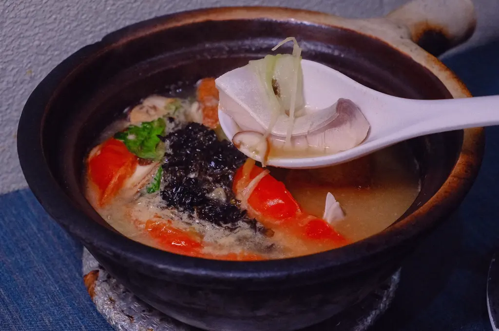 Close-up fish head soup with collagen-rich fish broth, napa cabbage, tomatoes and spring onions, showcasing the rich texture and flavour of traditional fish head soup.