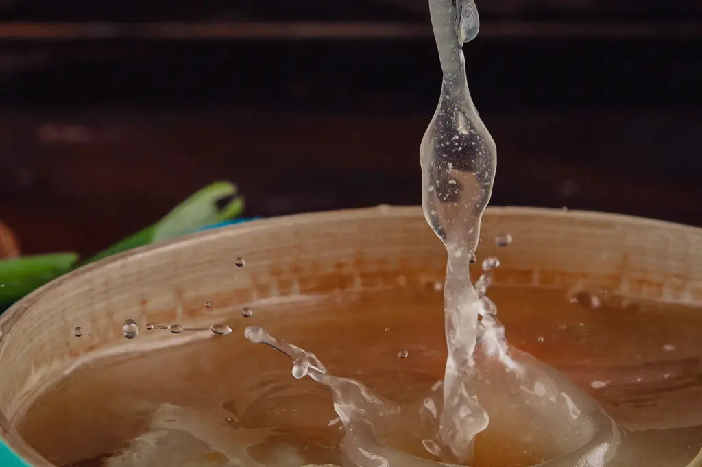 A close-up action shot captures clear, delicate broth splashing into a wooden bowl.