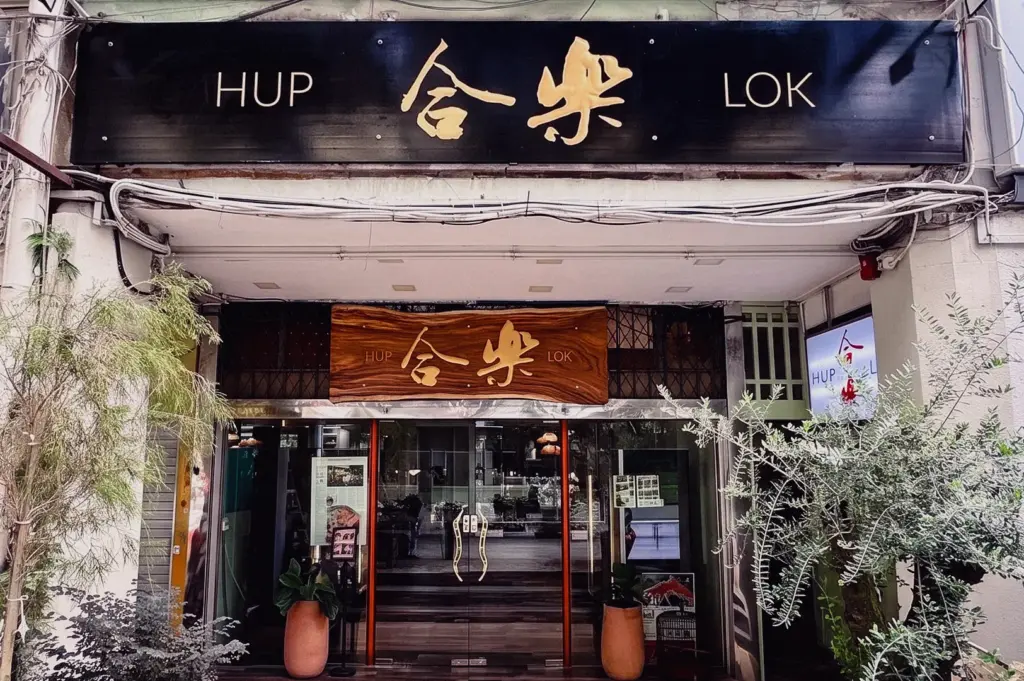 A wide straight-on exterior shot displays the wooden storefront and entrance of Hup Lok restaurant located on Havelock Road.